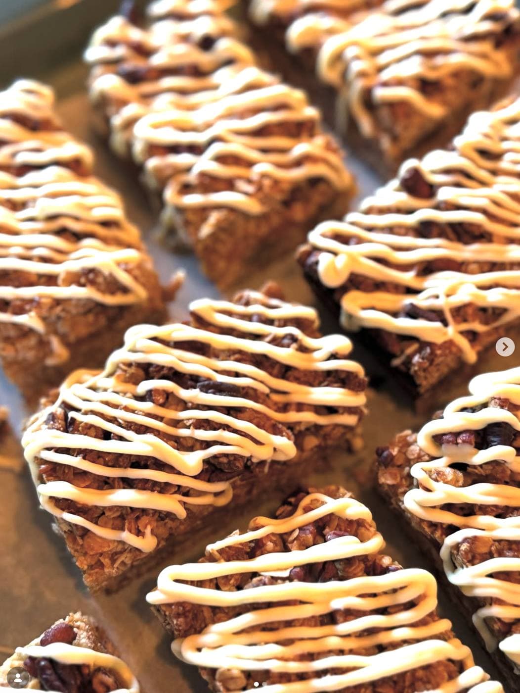 A tray of oat and cranberry flapjack squares drizzled with white chocolate icing