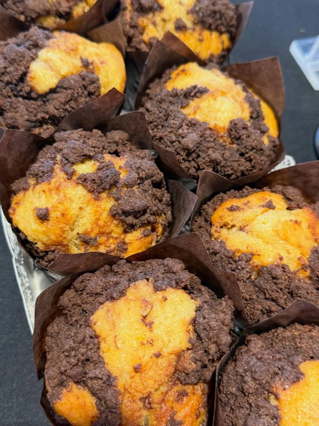 Orange and chocolate streusel muffins in brown paper cases with thick chocolate crumble topping