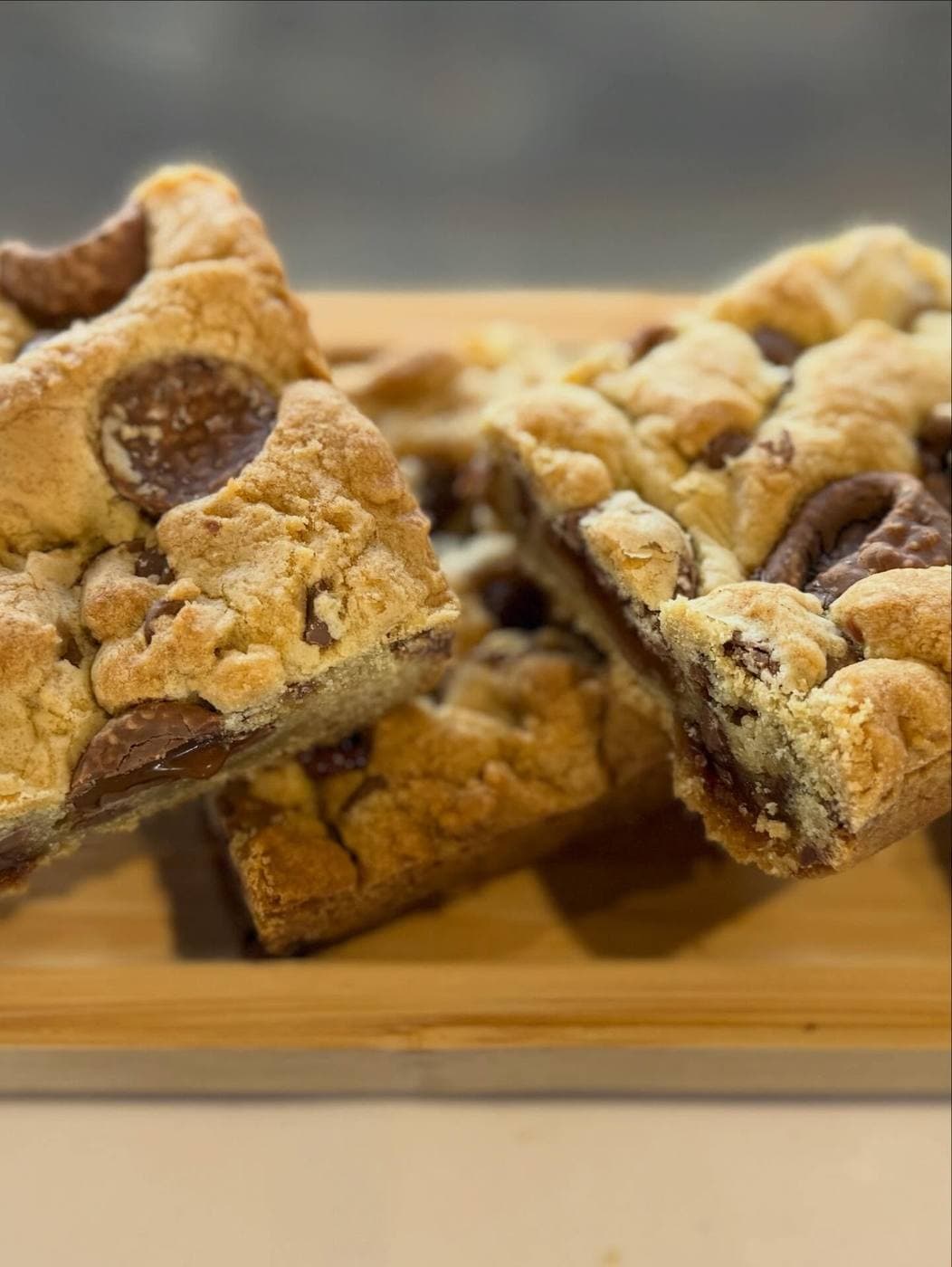 Stack of Rolo cookie bars cut into squares on a wooden board, chocolate caramel centres visible